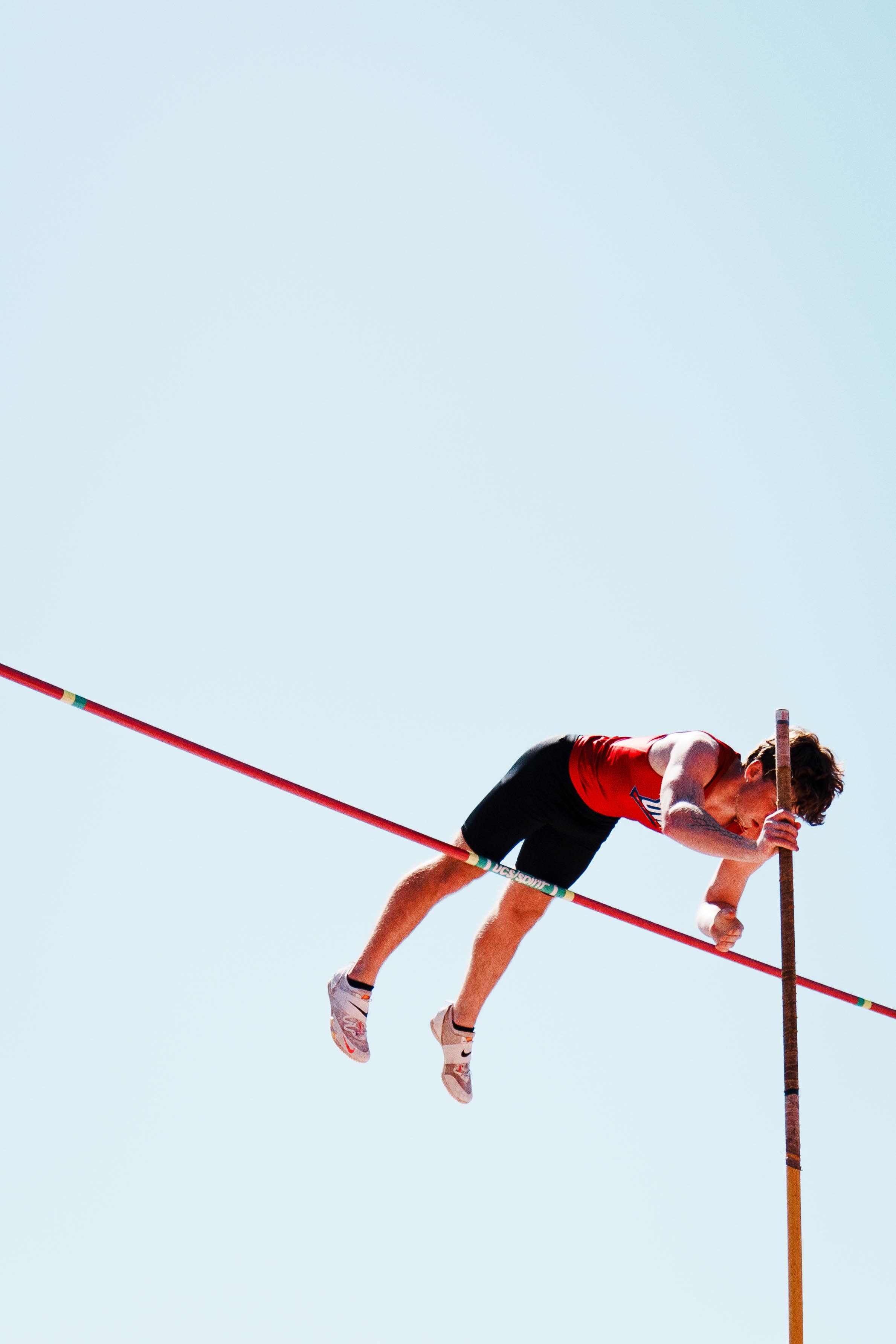 Pole vaulter midair over bar in sky
