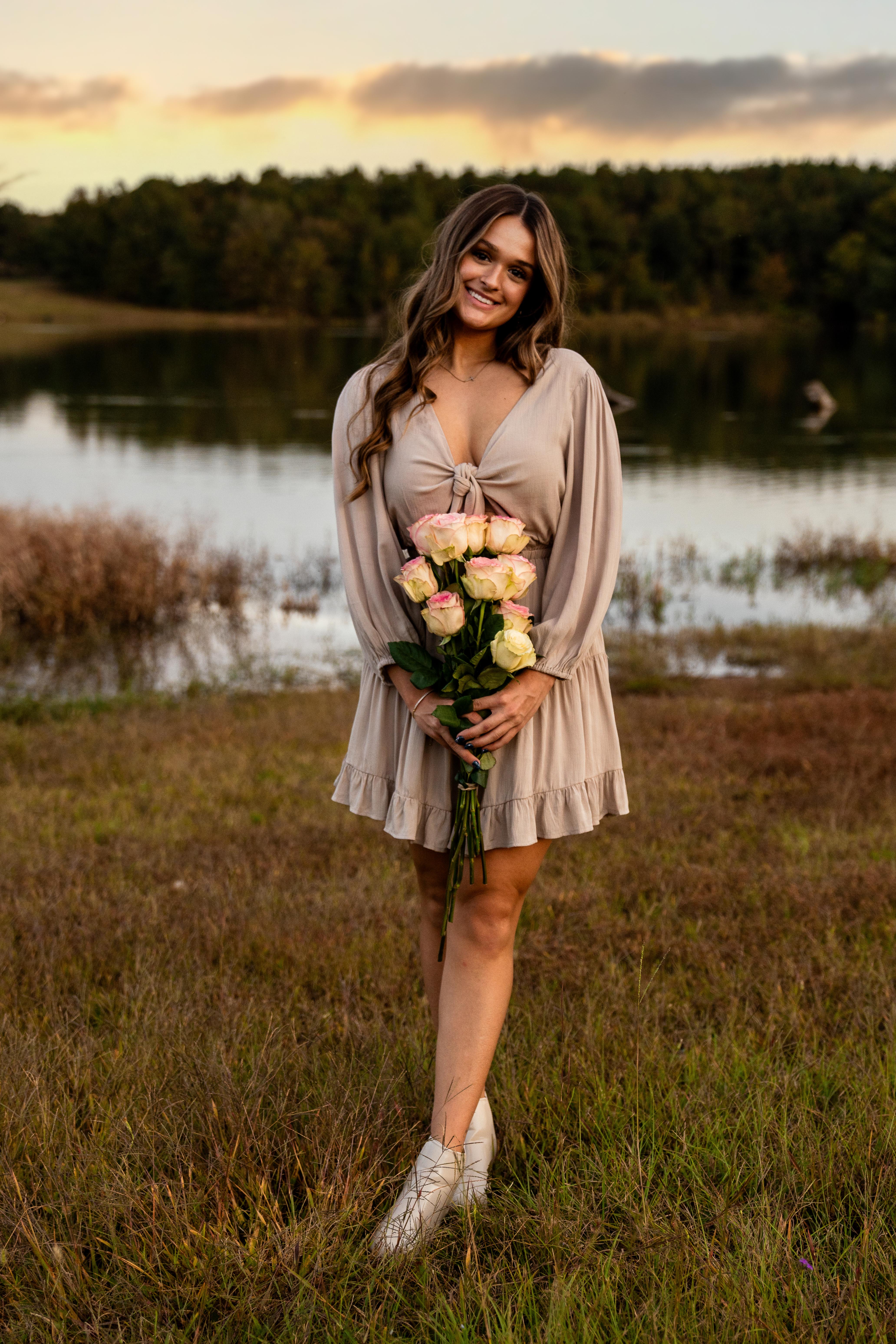 Girl holding flowers in front of lake